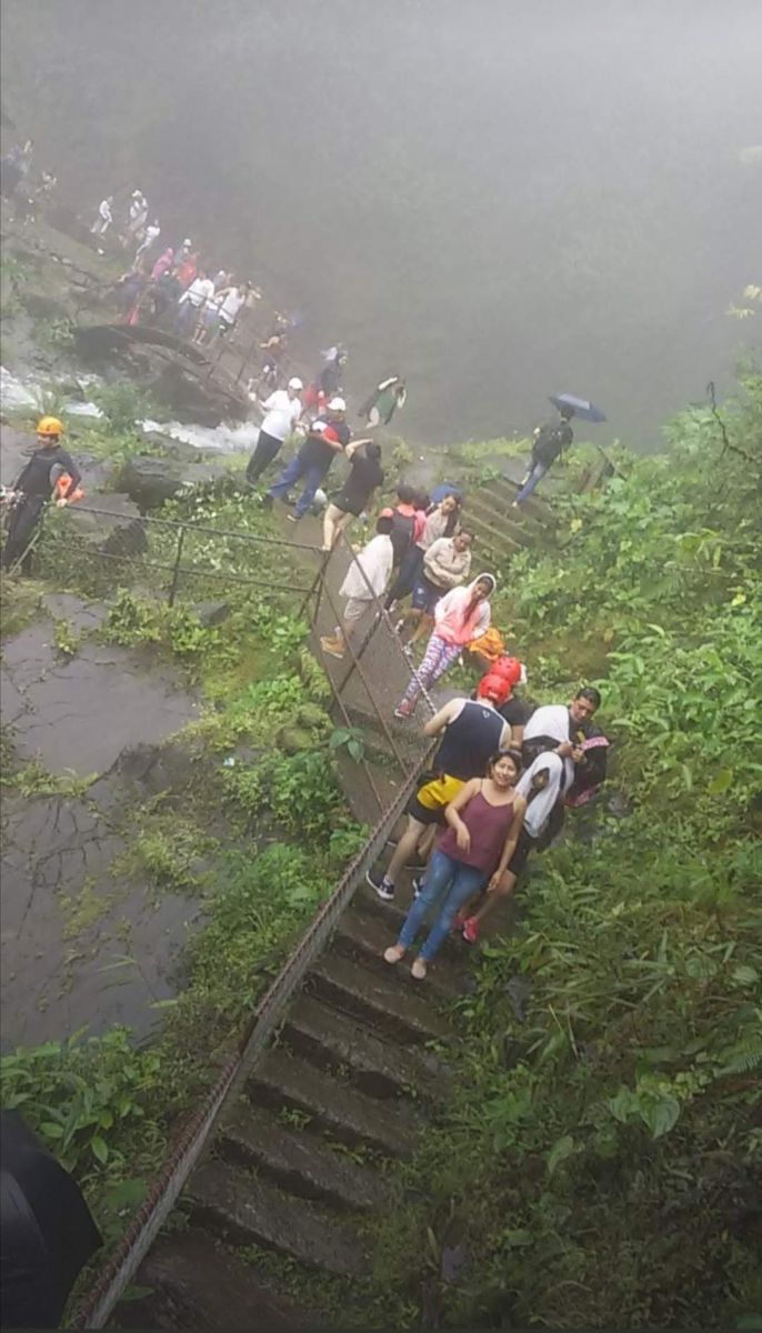Visitantes bajando las escalinatas hacia las cascadas entre la neblina
